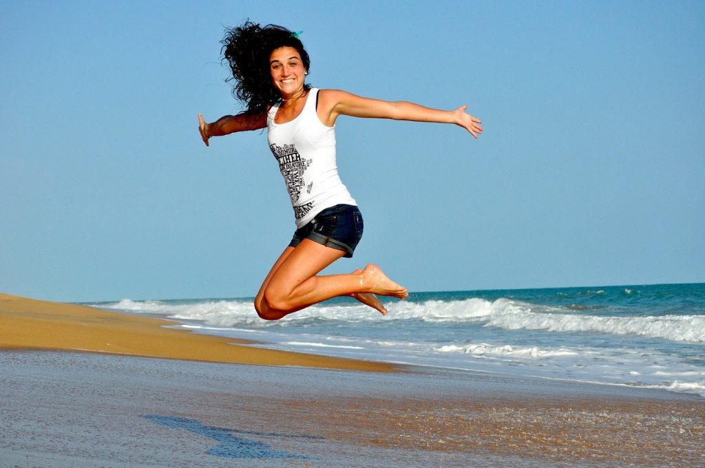 jeune femme souriante qui saute sur la plage