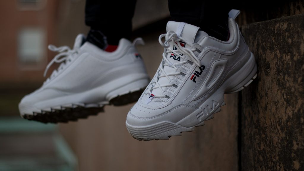 pieds d'une personne portant des baskets blanches