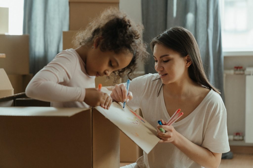mère et sa fille qui dessine sur un carton de déménagement